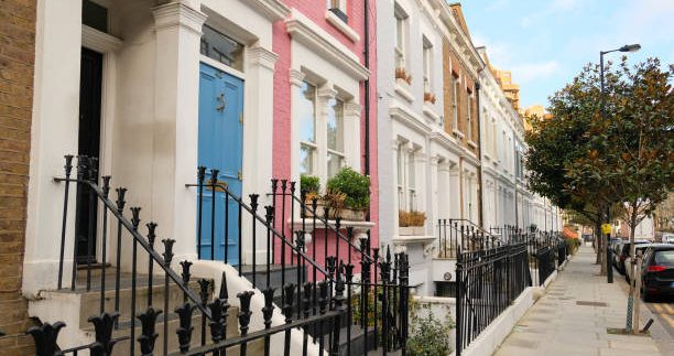 Typical Victorian terraced houses in England. Exterior view of cozy residential buildings in London with metal fence, several floors, windows and front door with molding. Real estate, Living apartments.